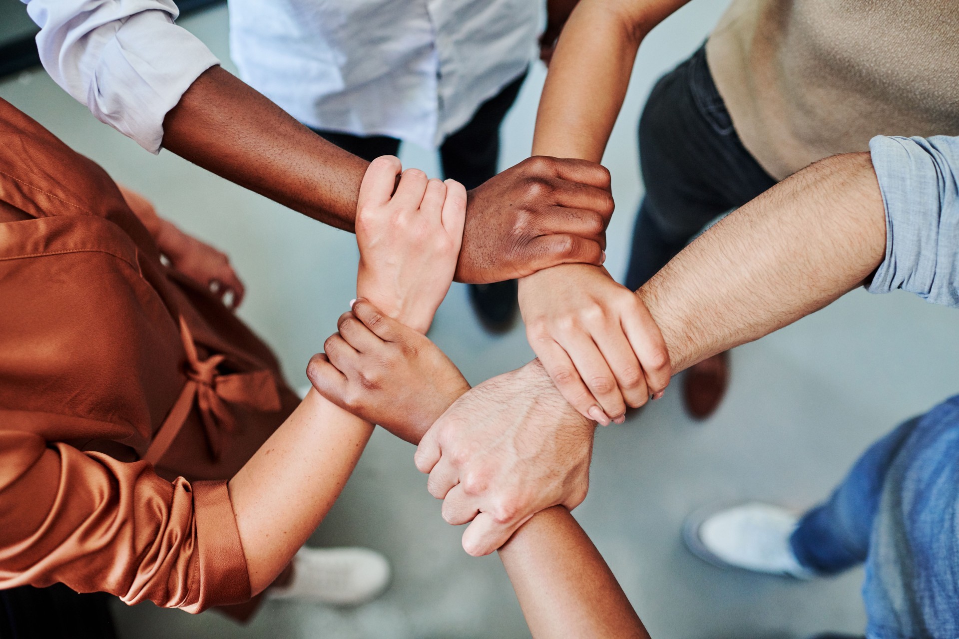 High angle shot of a group of businesspeople holding one another's wrists in a circular formation